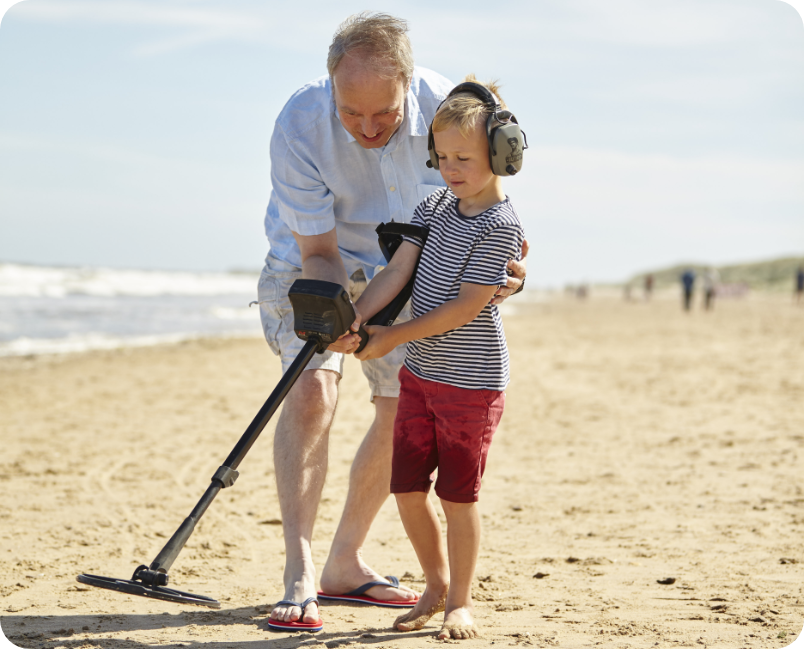 Man and child at the beach with a metal detector