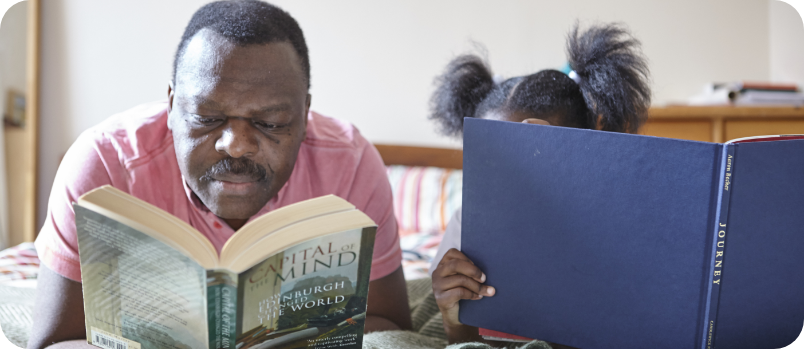 Father and daughter on bed reading books