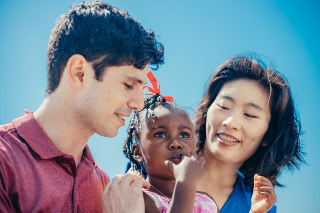 Two adults smiling with a young girl